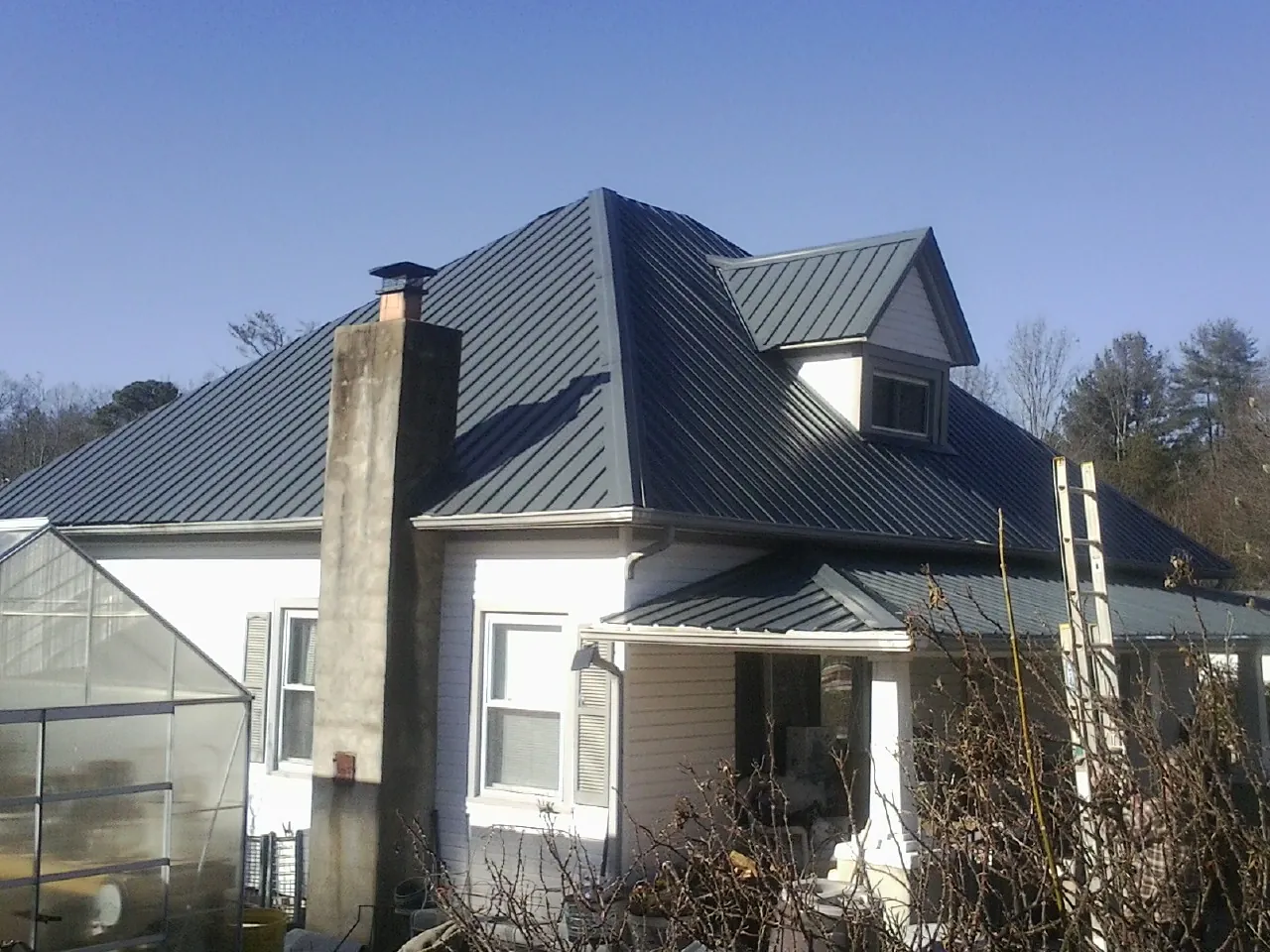 Dark blue standing seam metal roof on a white farmhouse with dormer — Slate & Tile Roof Repair by Roofing Brothers in Westville