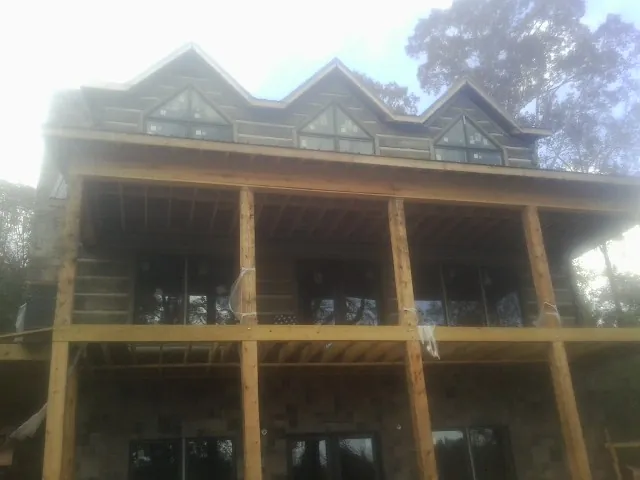 Dormers and porch framing on a large log home under construction — Roof Coating work by our crew in Westville