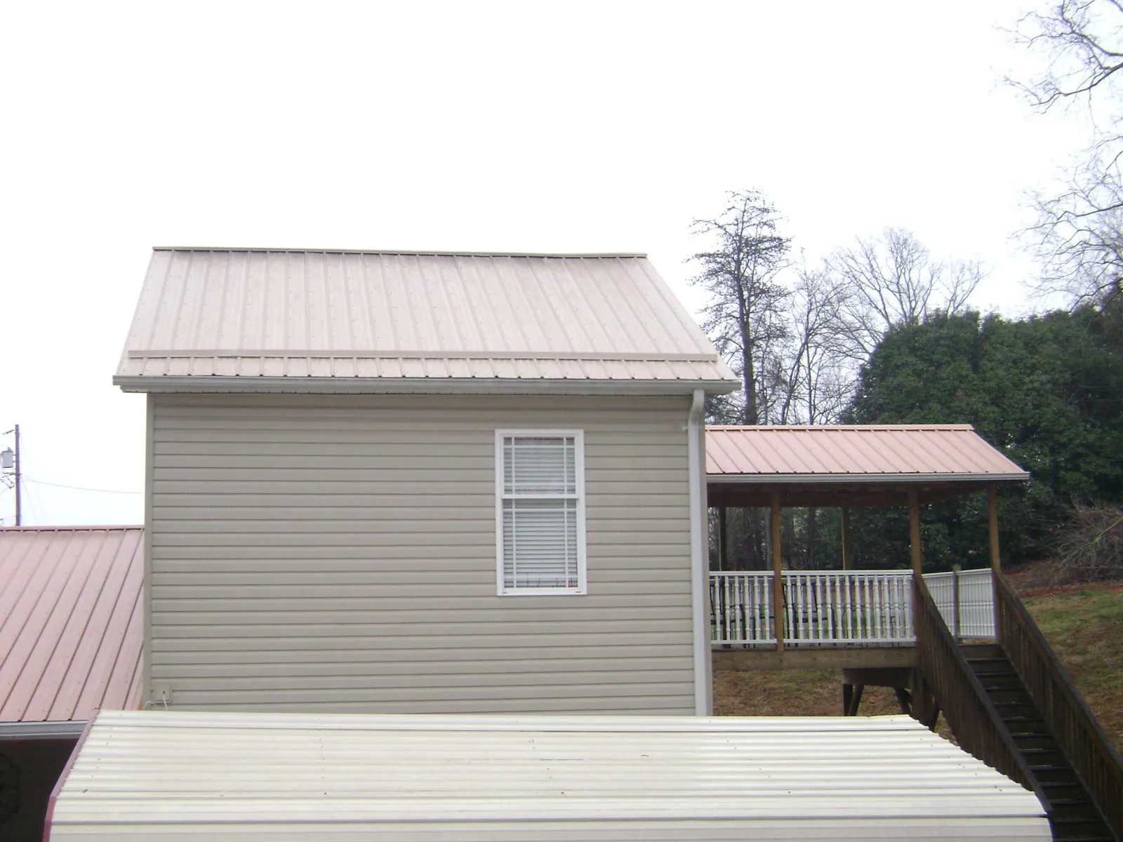Tan metal roofs on a two story addition and attached porch, from a Roof Replacement job in Westville